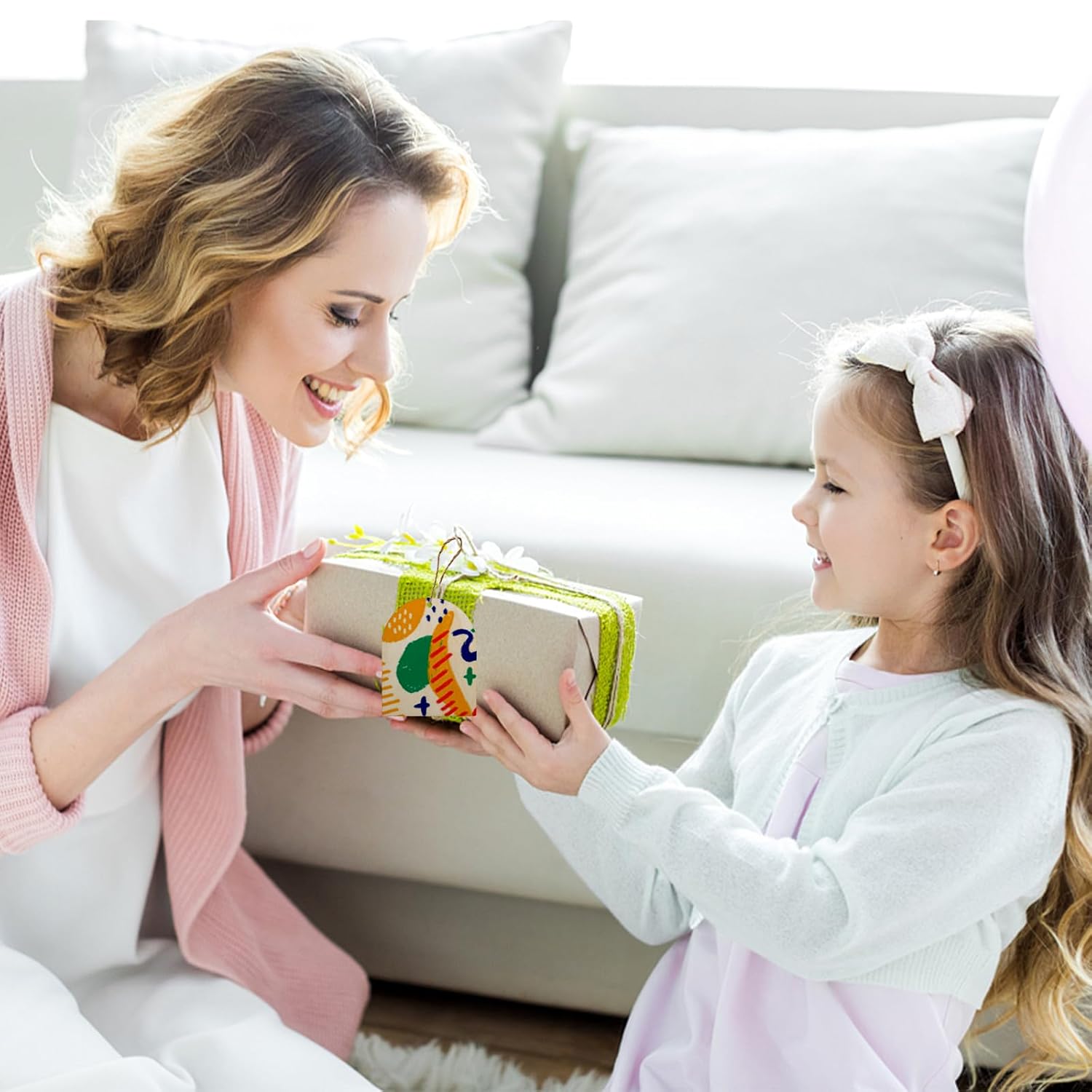 Woman and young girl exchanging a gift in a cozy living room.