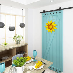 Dining room with a blue barn door featuring a yellow sunflower design.