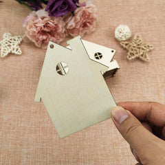 Metal birdhouse-shaped punch on a textured surface with flowers in the background
