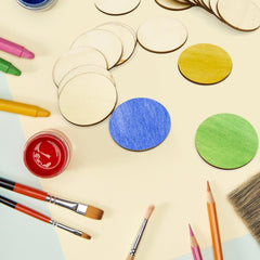 Colorful circular wooden shapes, paintbrushes, and paint containers on a light surface