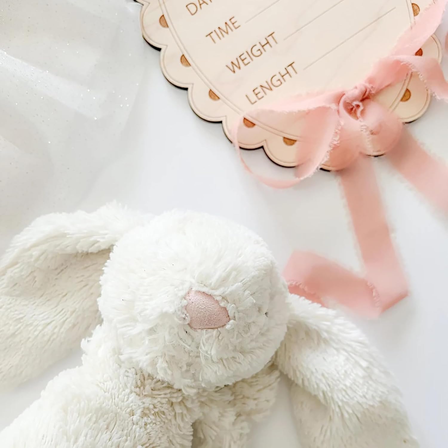 White plush bunny with a pink bow and measurement card on a white background