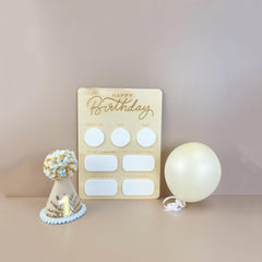 Wooden birthday card with white circles, a small cake model, and a balloon on a beige background