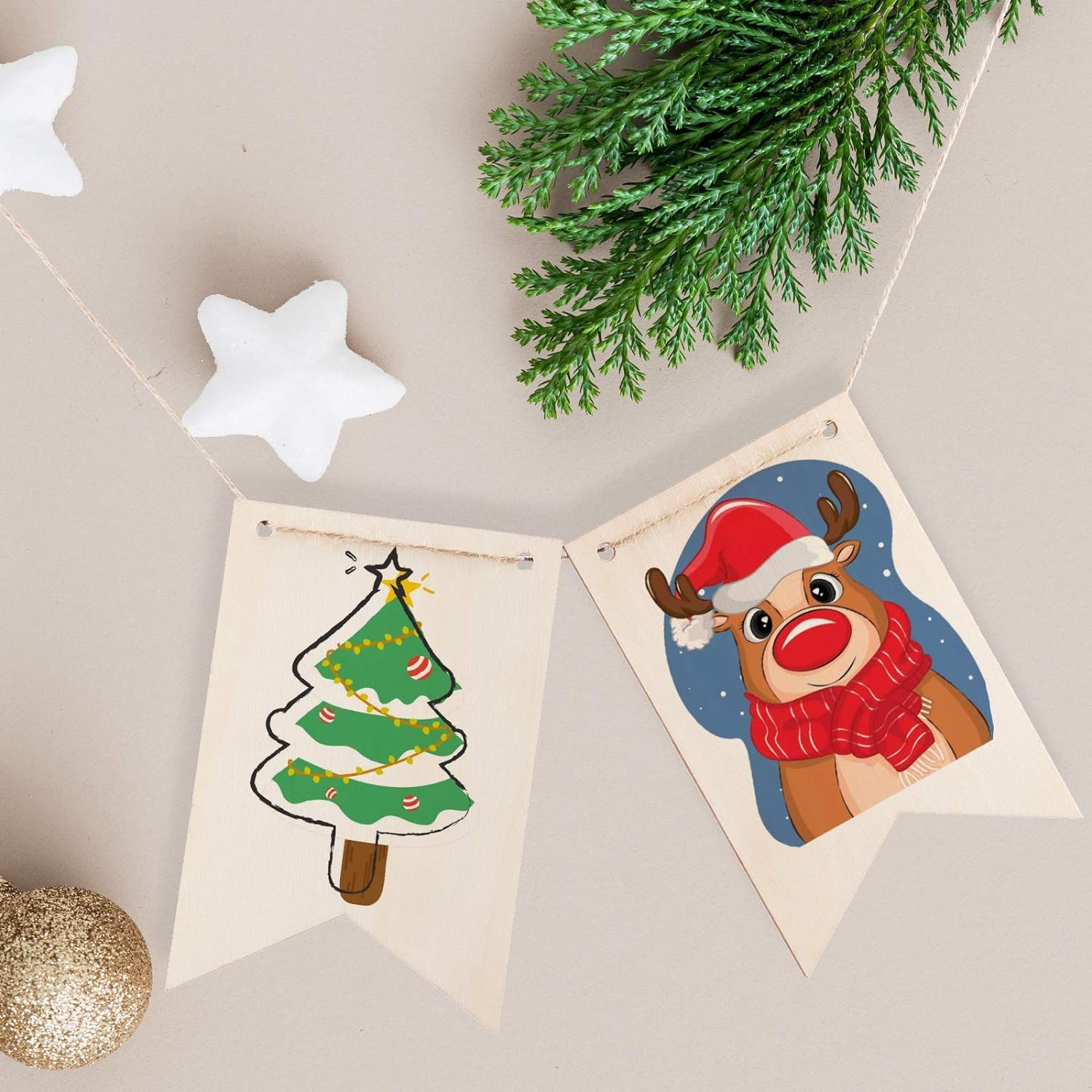 Two Christmas-themed cards with a reindeer and a tree on a beige background with greenery and stars.