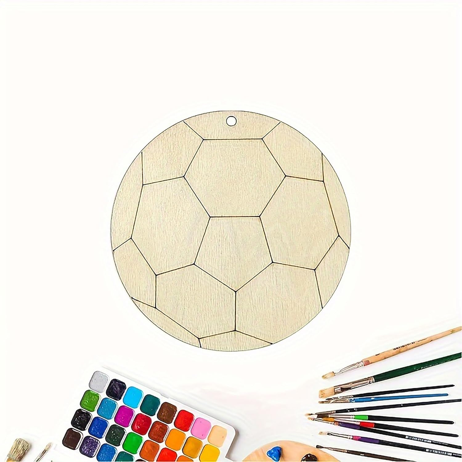 Wooden geometric pendant with paintbrushes and color swatches on a white background