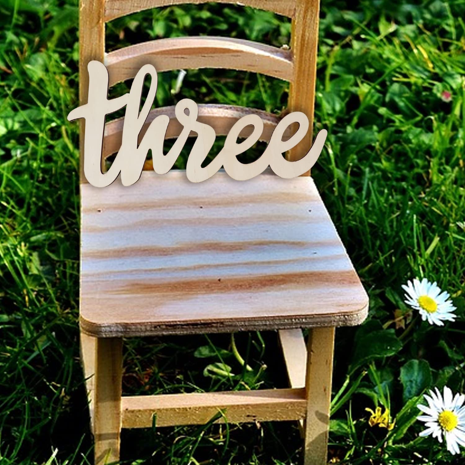 Wooden chair with 'three' sign on grass