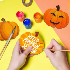 Person decorating a pumpkin-shaped ornament with 'Hello Pumpkin Season' text on a colorful background.