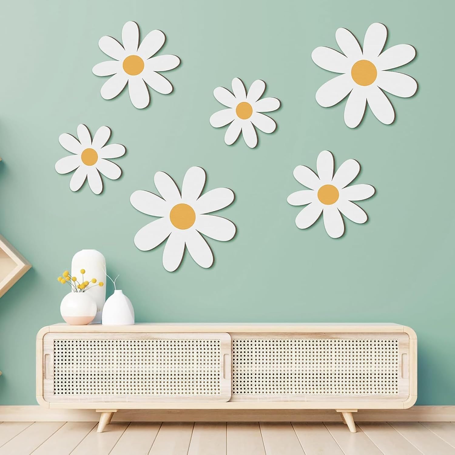 White daisy wall decals on a light green wall above a wooden console table.