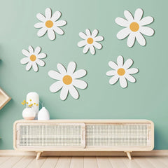 White daisy wall decals on a light green wall above a wooden console table.