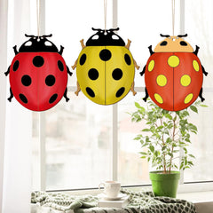 Three colorful ladybug-shaped paper lanterns hanging by a window.