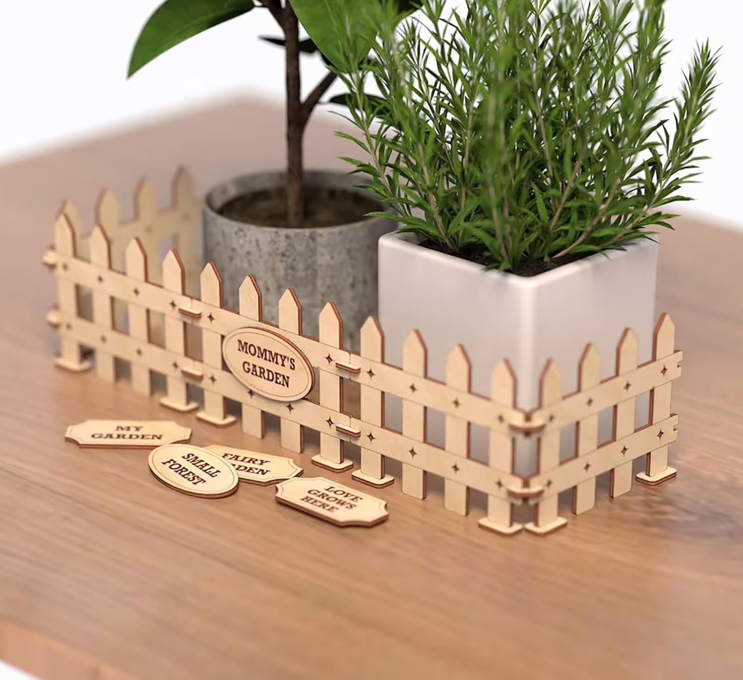 Small wooden fence with potted plants on a wooden surface