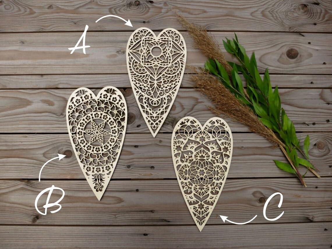 Three ornate heart-shaped cutouts on a wooden surface with decorative elements.