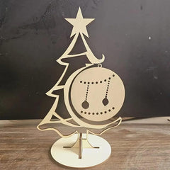 Decorative Christmas tree ornament with a star on top and a ball with cut-out designs, placed on a wooden surface.