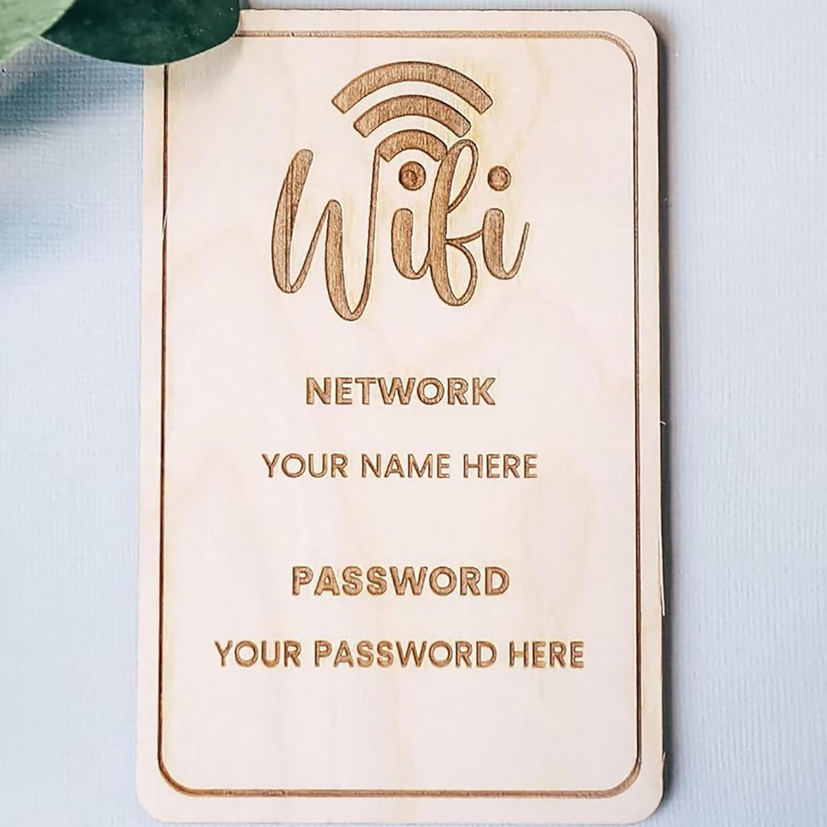 Wooden plaque with engraved text for WiFi network details on a light blue background