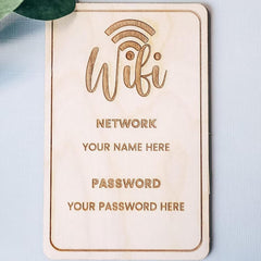 Wooden plaque with engraved text for WiFi network details on a light blue background