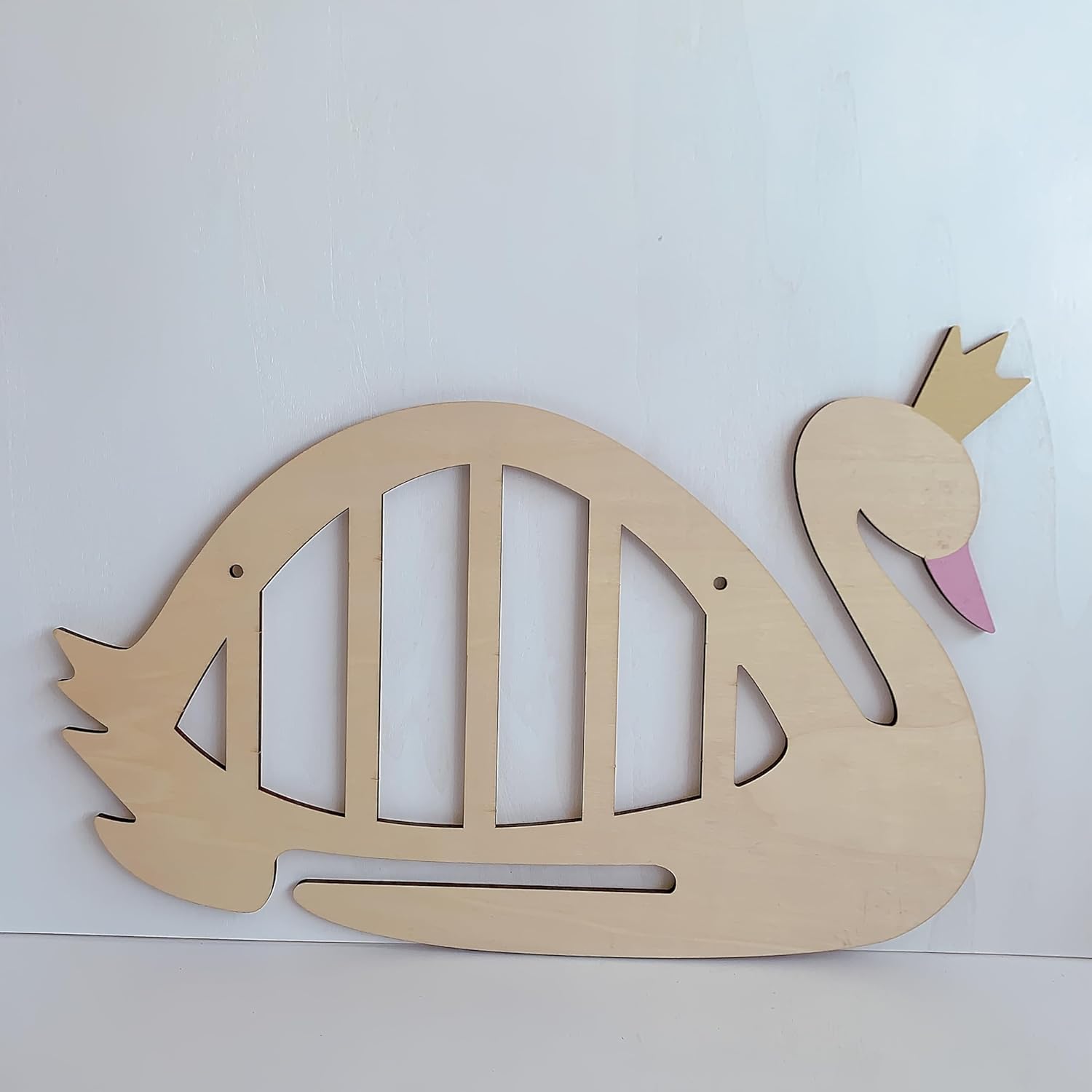 Wooden swan cutout with a pink beak on a white background
