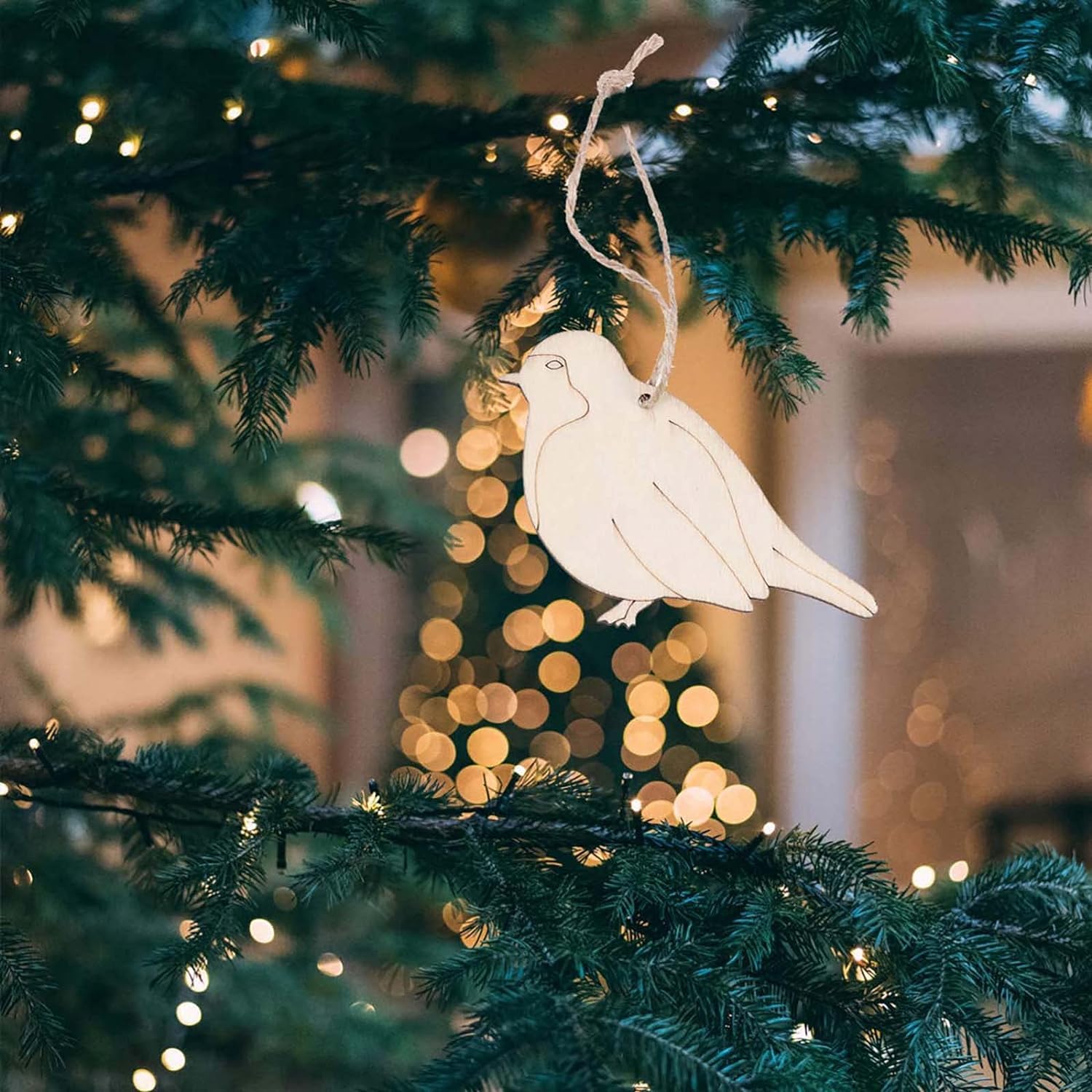 White dove ornament hanging on a Christmas tree with blurred lights in the background