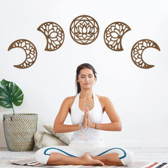 Woman in a white outfit meditating with decorative wall art in the background