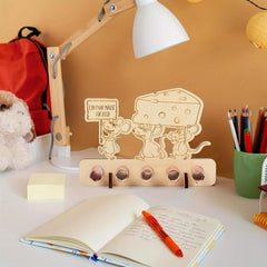 Desk setup with a decorative mouse and cheese sign, notebook, pen, and lamp.
