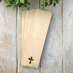 Three wooden bookmarks with cross designs on a rustic wooden surface.