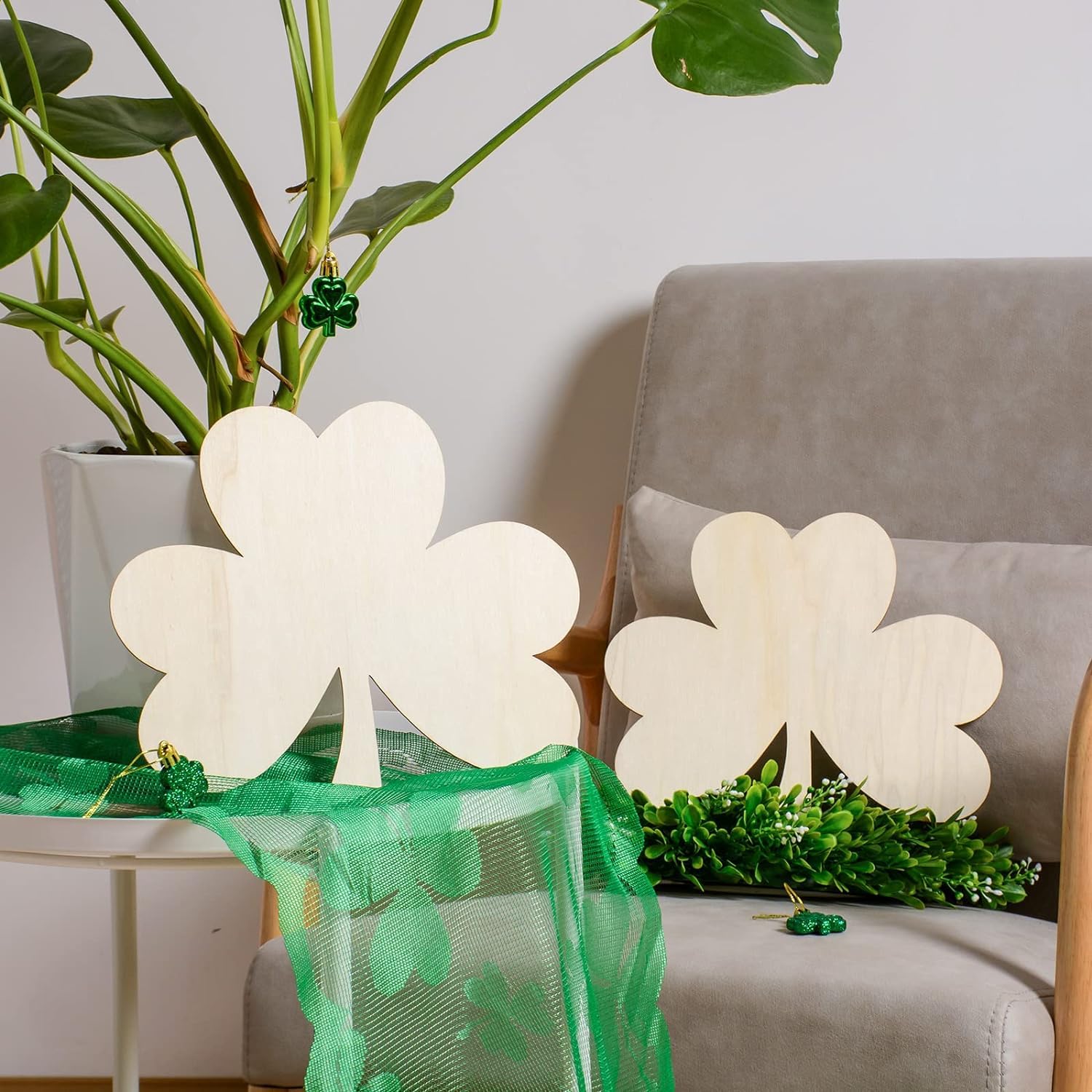 Decorative shamrock-shaped lamps on a table with a plant and pillow in the background.