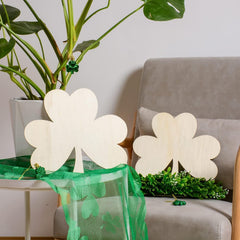 Decorative shamrock-shaped lamps on a table with a plant and pillow in the background.