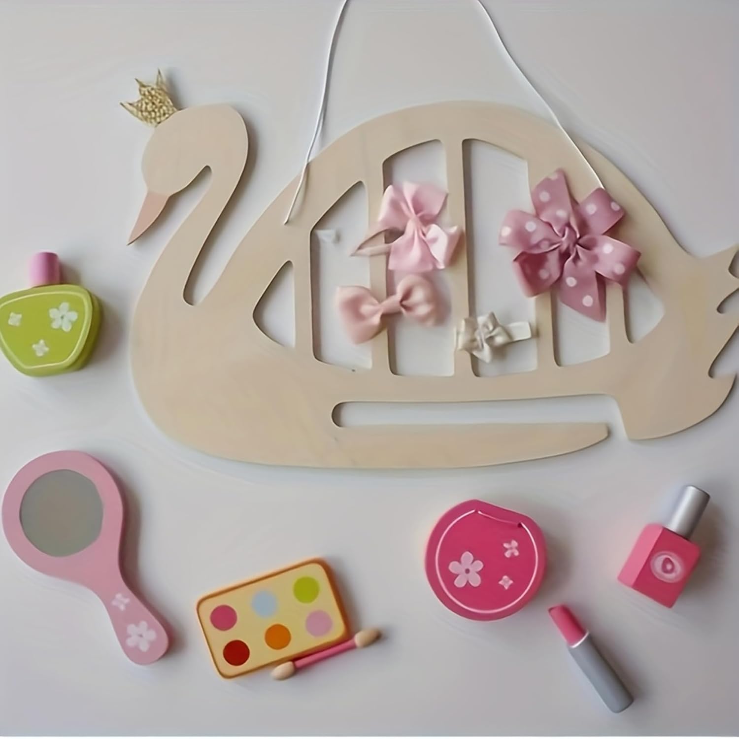 Wooden swan with decorative bows and small cosmetic items on a light background