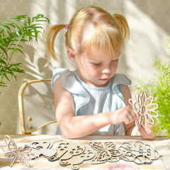 Child playing with wooden cutouts on a table with plants in the background