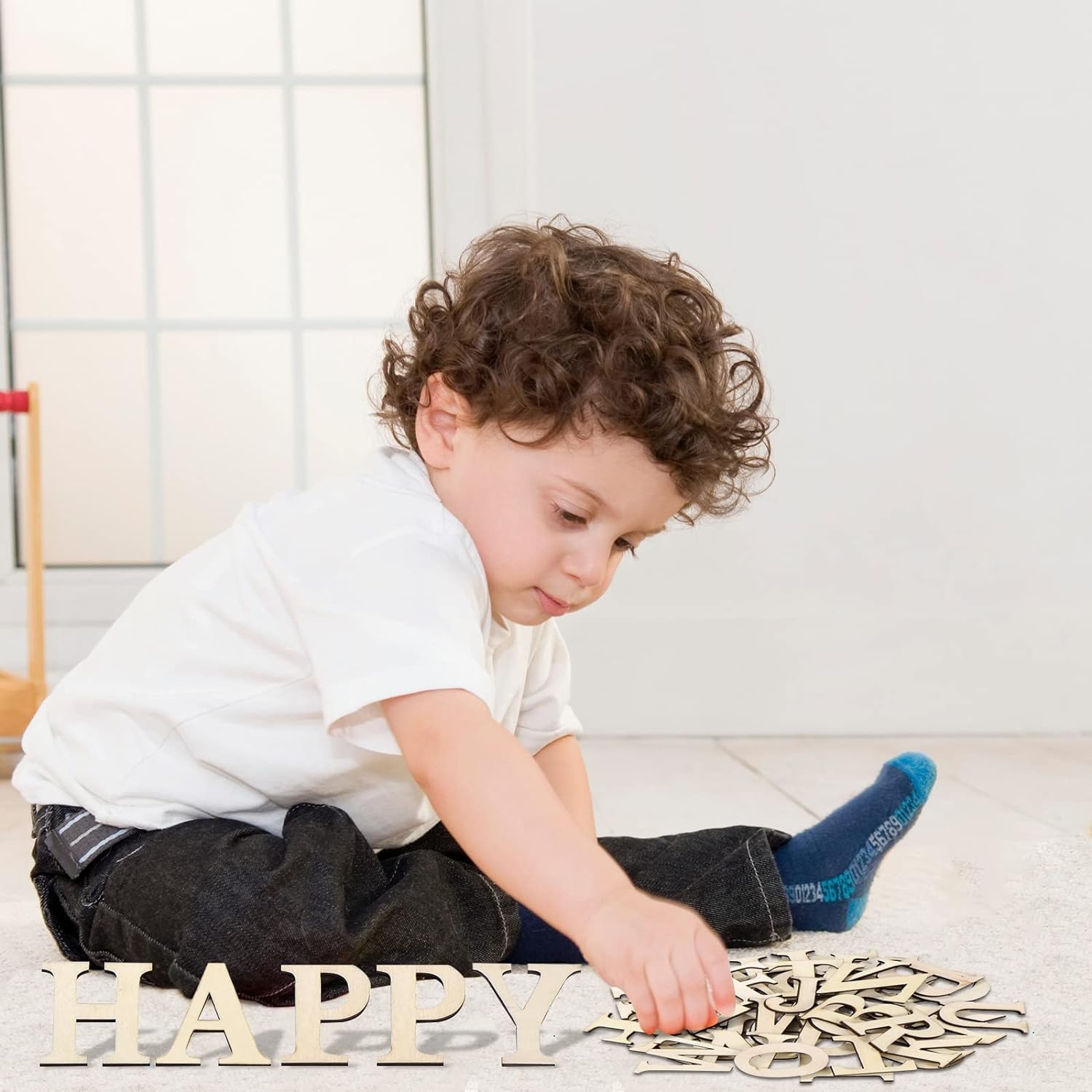Child playing with wooden letters on a light-colored floor.