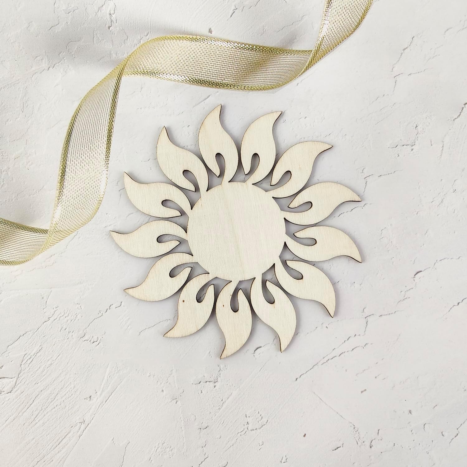 Decorative sun-shaped ornament with a gold ribbon on a light gray background