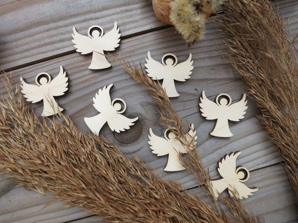Wooden angel ornaments on a wooden surface with dried grasses.