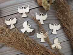 Wooden angel ornaments on a wooden surface with dried grasses.