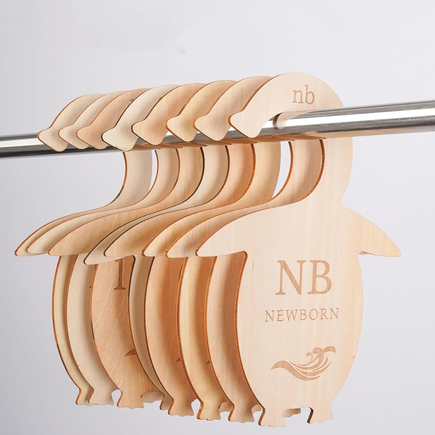 Set of wooden baby hangers with 'NB' and 'NEWBORN' branding on a light gray background