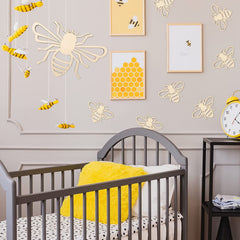Nursery room with gray crib, yellow blanket, and bee-themed decor.