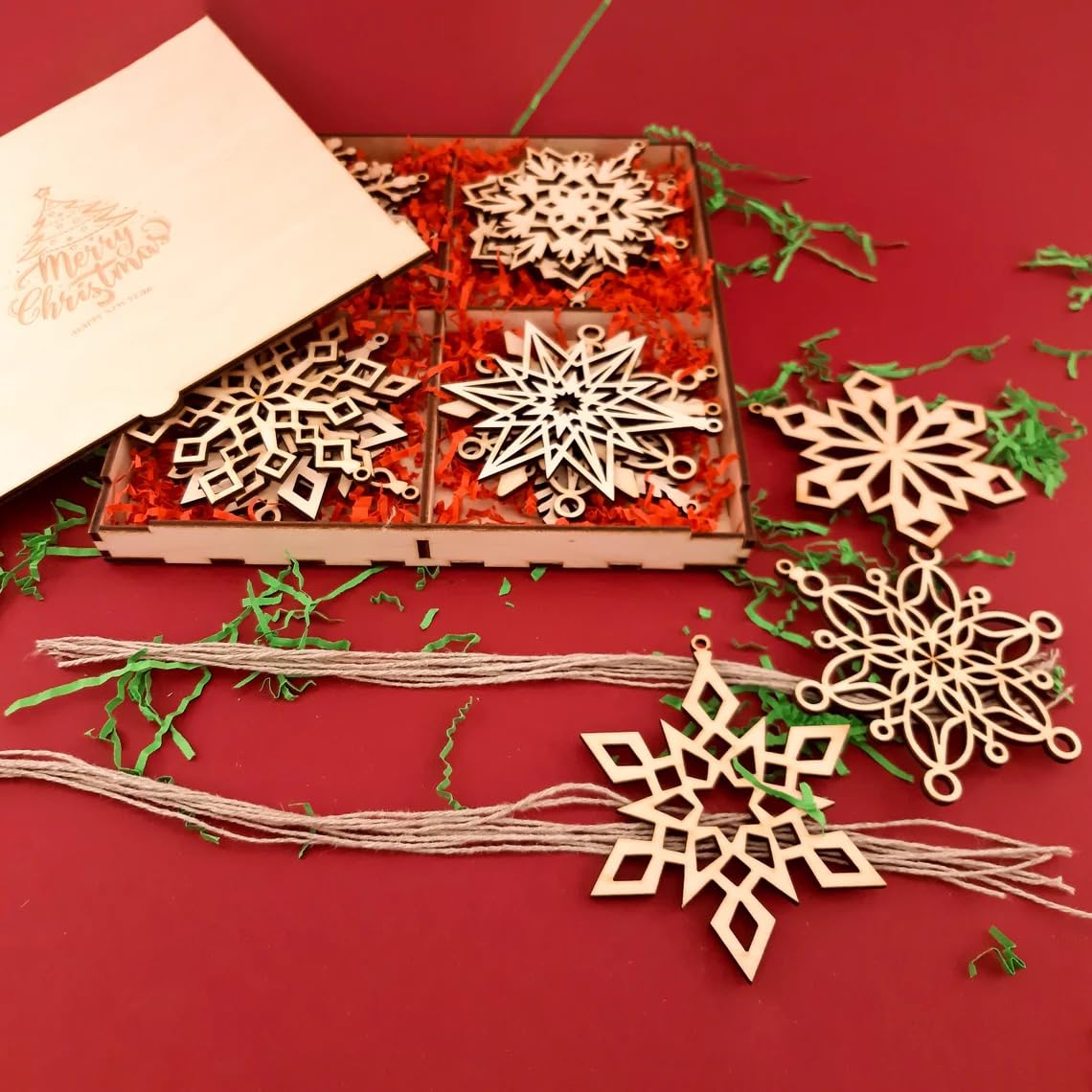 Wooden snowflake ornaments on a red surface with a box and decorative elements.