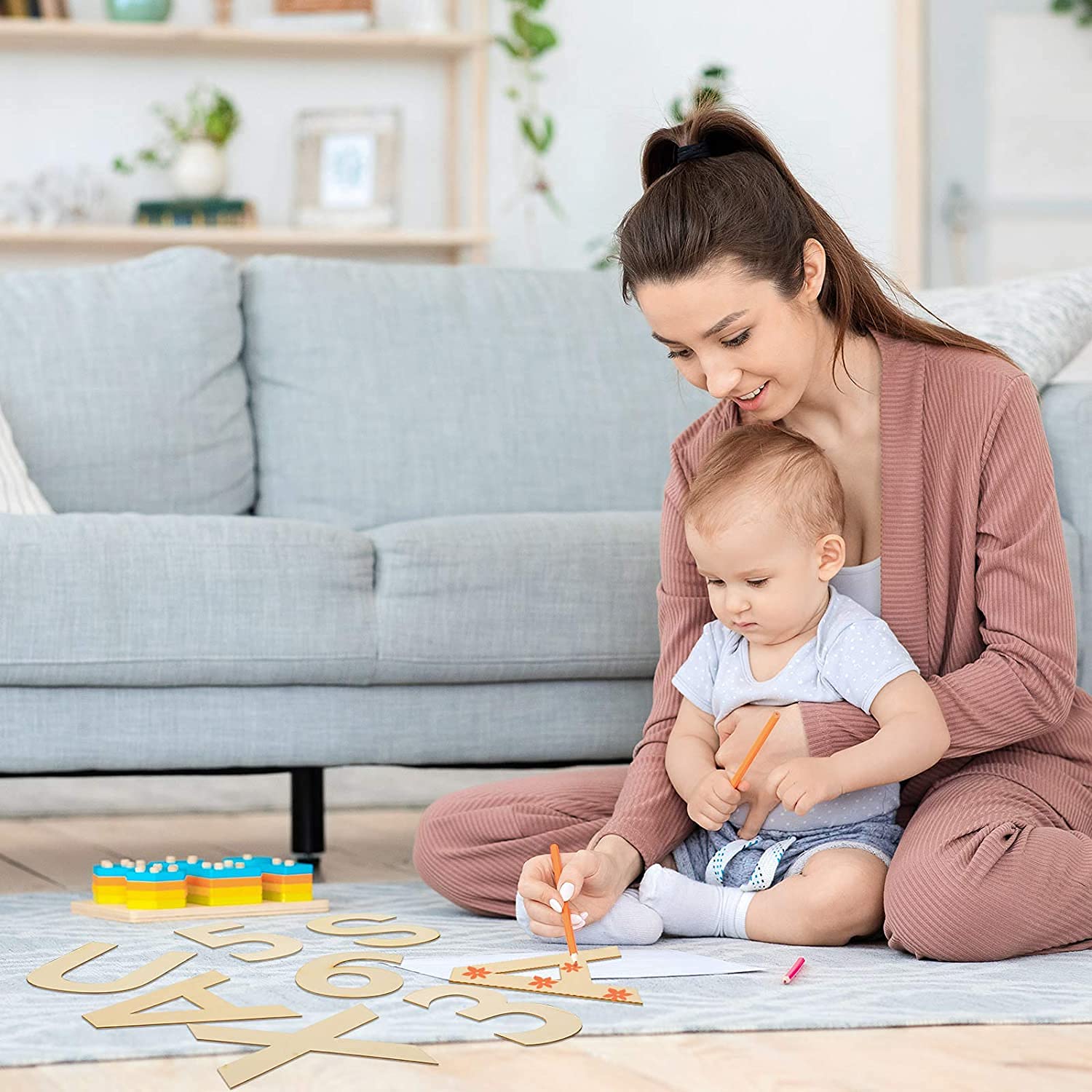 Woman and child playing with wooden letters on a rug in a living room.