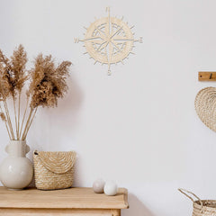 Decorative wall with compass, vase, and baskets on a wooden shelf against a white wall.