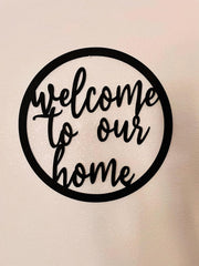 Decorative metal sign with 'welcome to our home' text on a beige background