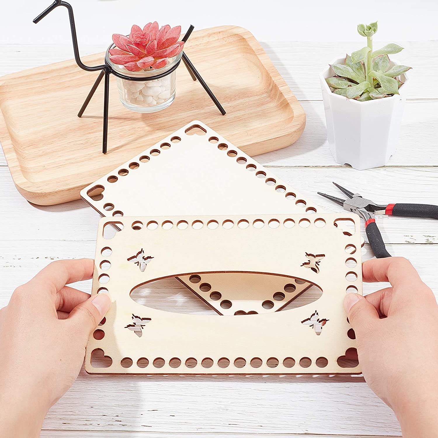 Wooden puzzle with butterfly design held by hands on a wooden surface with plants and tools.
