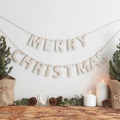 Merry Christmas banner with candles and pinecones on a wooden surface.