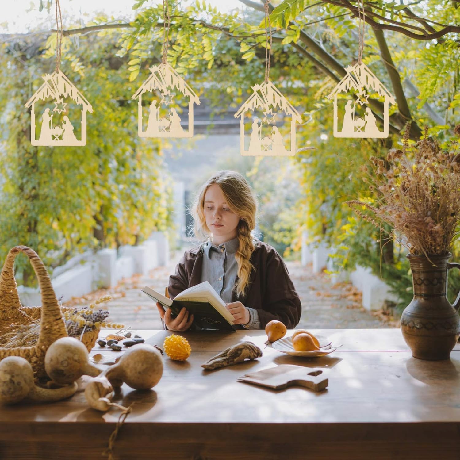 Young girl reading a book in a cozy room with hanging wooden houses and autumn decorations.