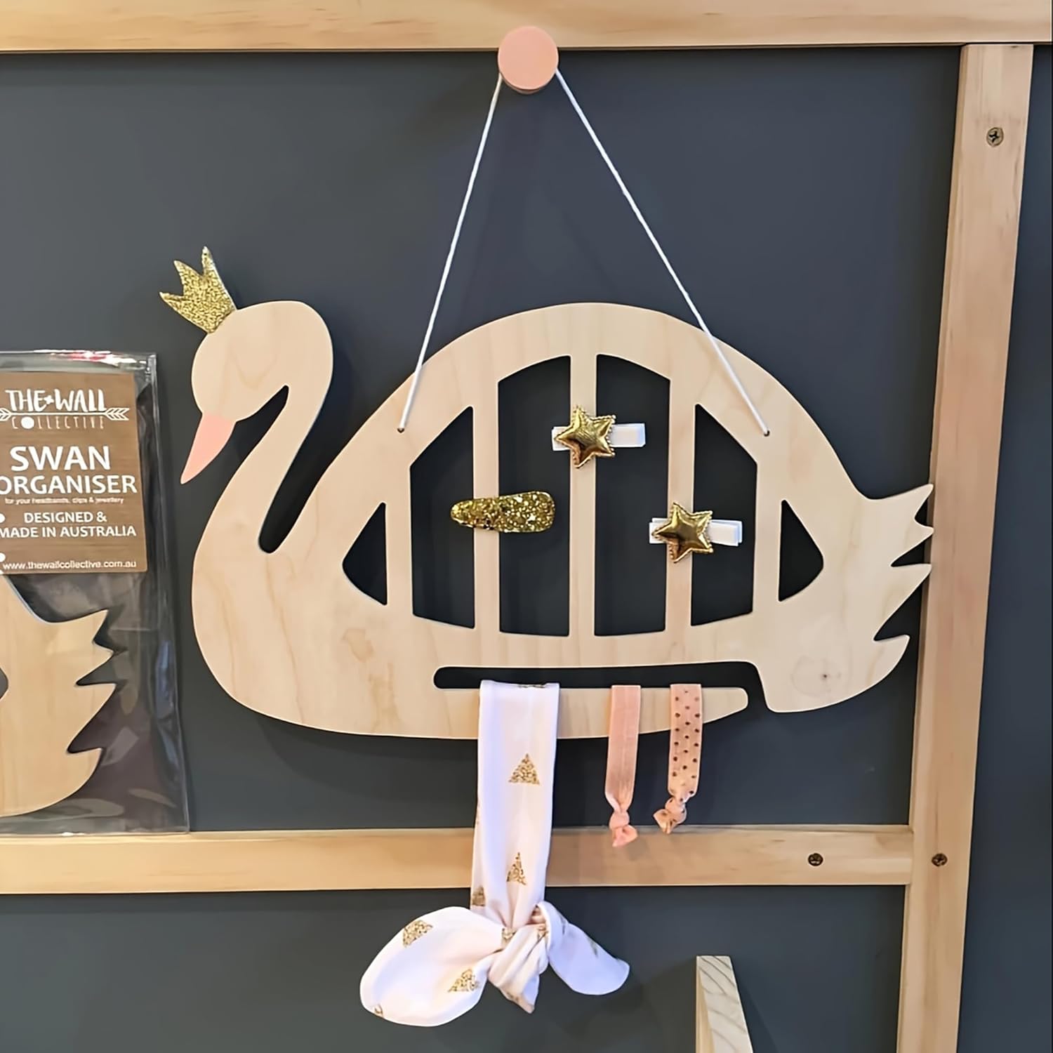 Wooden swan-shaped organizer with decorative items on a dark wall