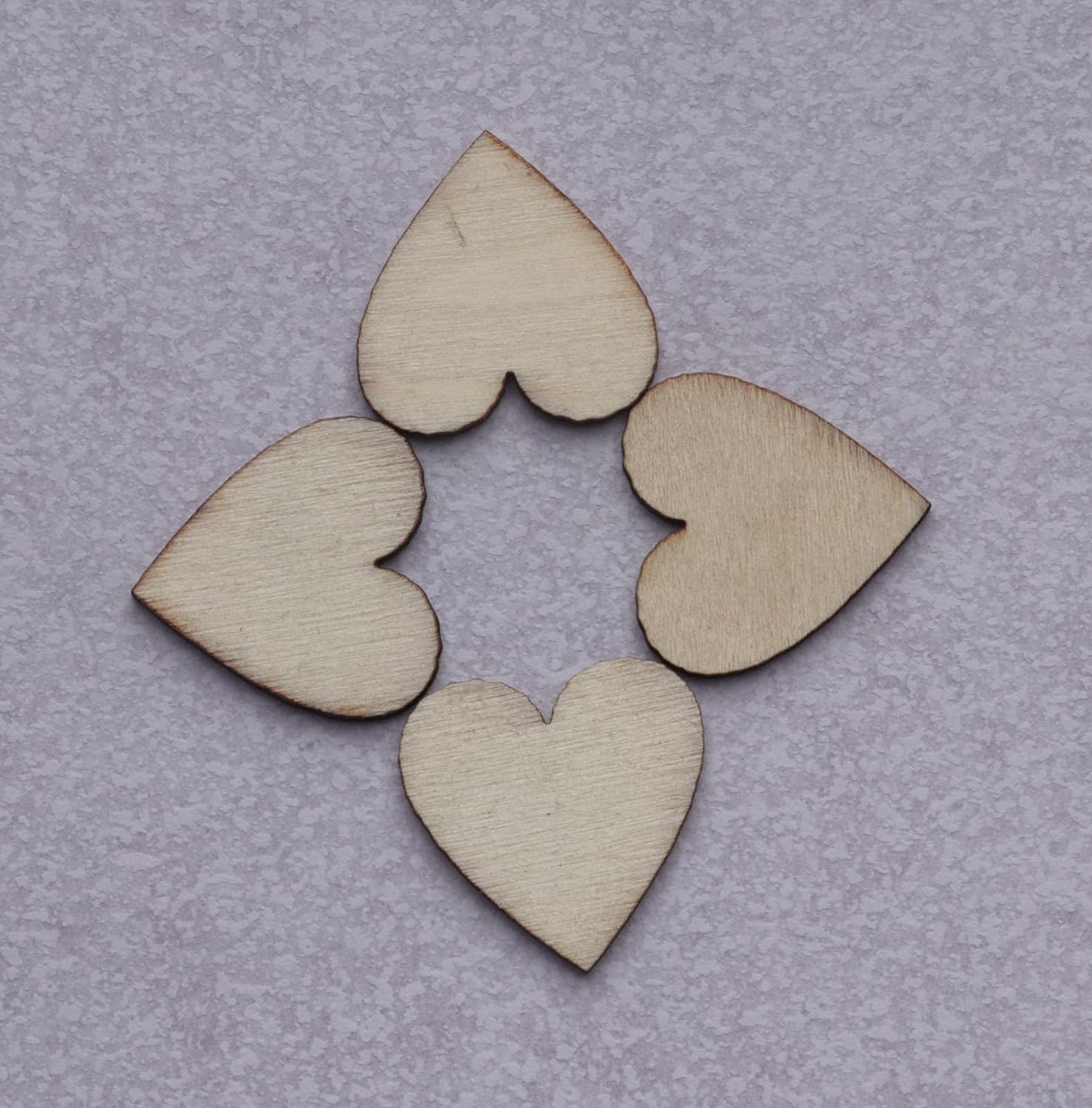 Four wooden heart shapes arranged in a circular pattern on a gray background