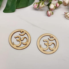 Two wooden om symbol coasters on a light surface with flowers in the background