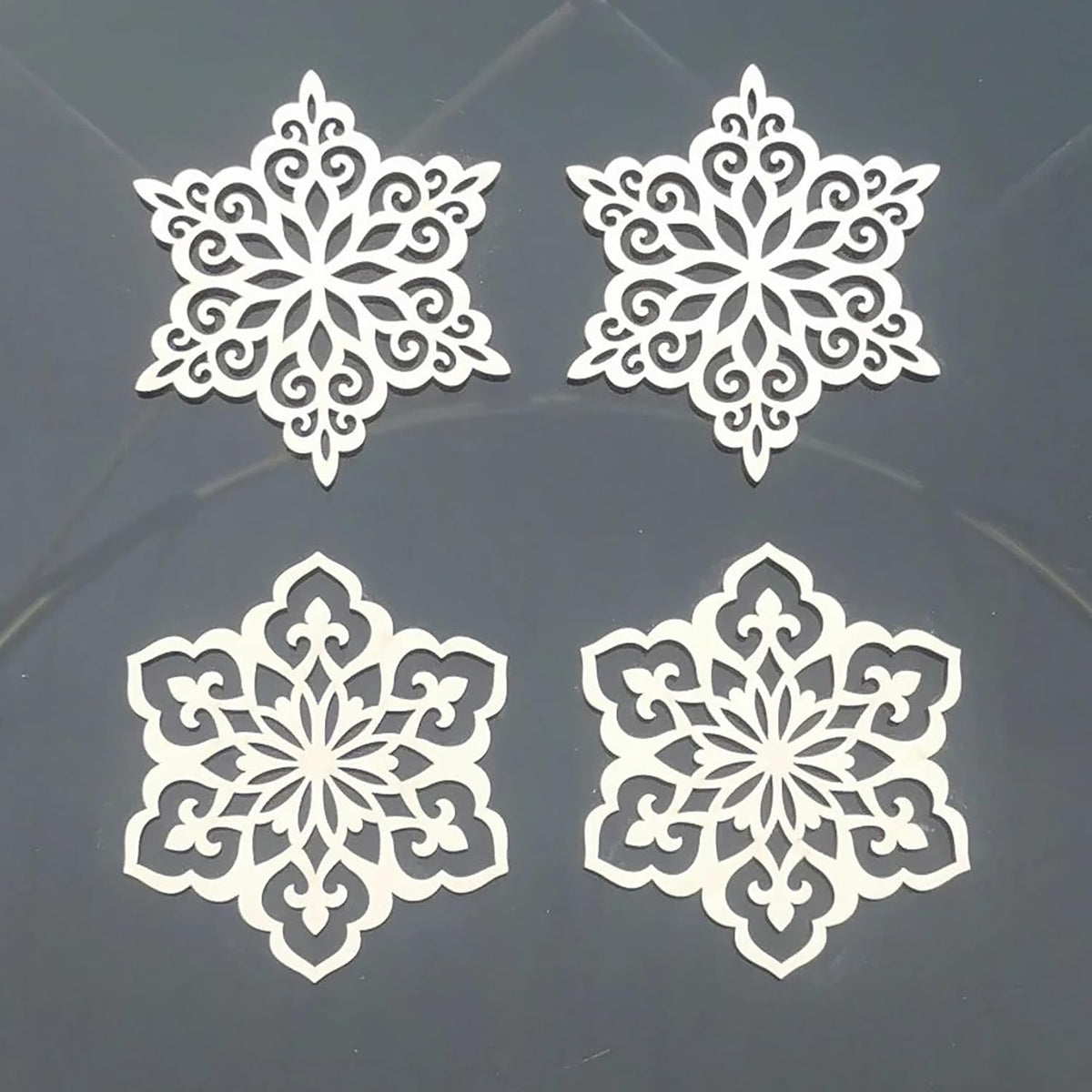 Four white snowflake-shaped cutouts on a dark background