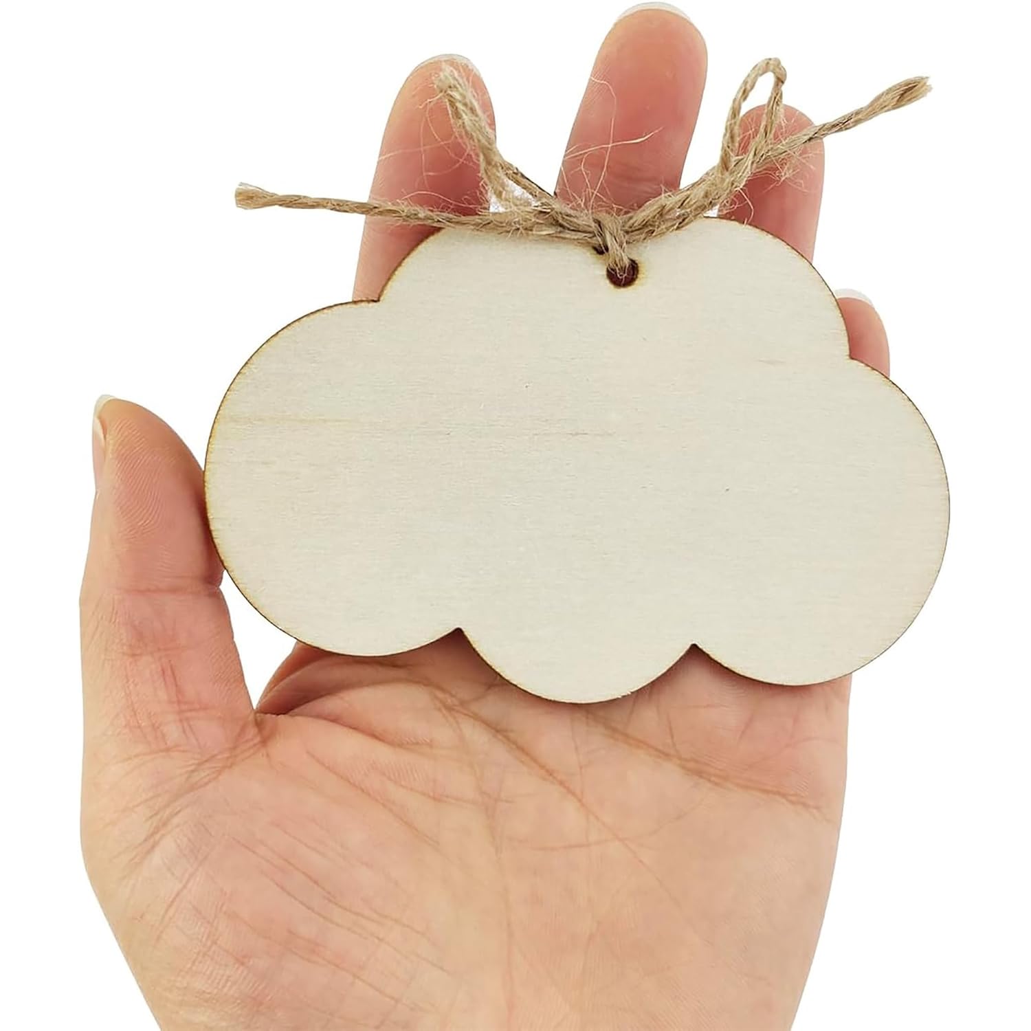 Wooden cloud-shaped ornament with twine held in a hand against a white background