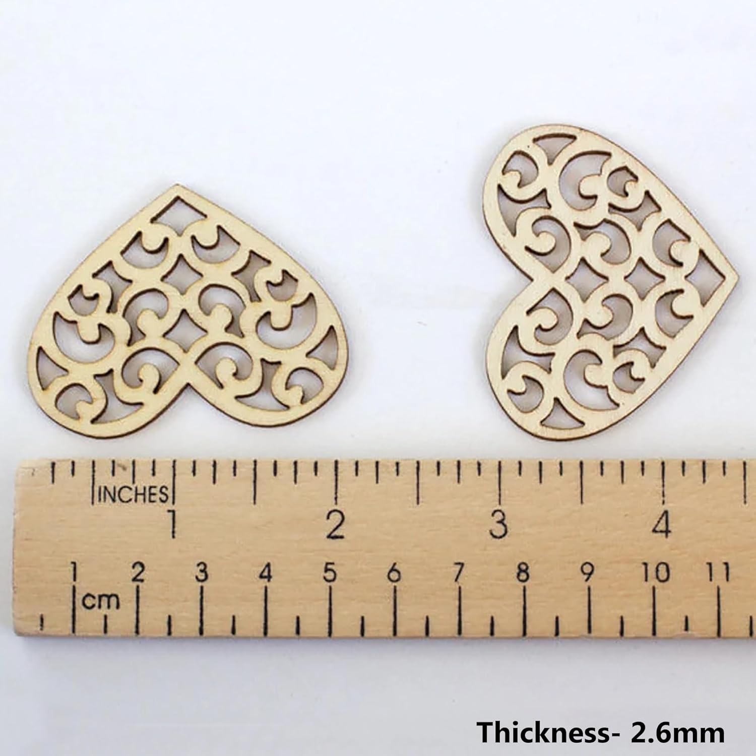 Two decorative wooden heart shapes with a ruler showing their thickness on a white background.