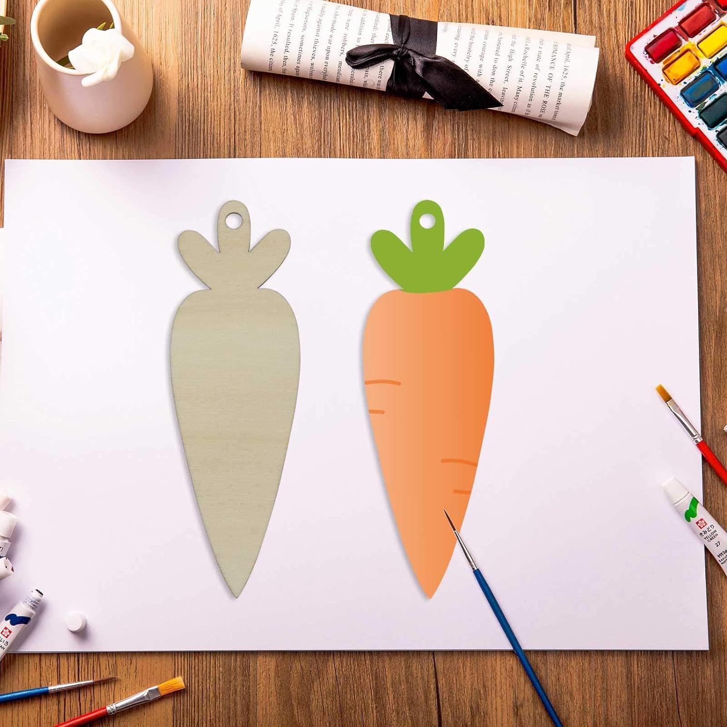 Carrot-shaped cutouts on a piece of paper with art supplies on a wooden table.