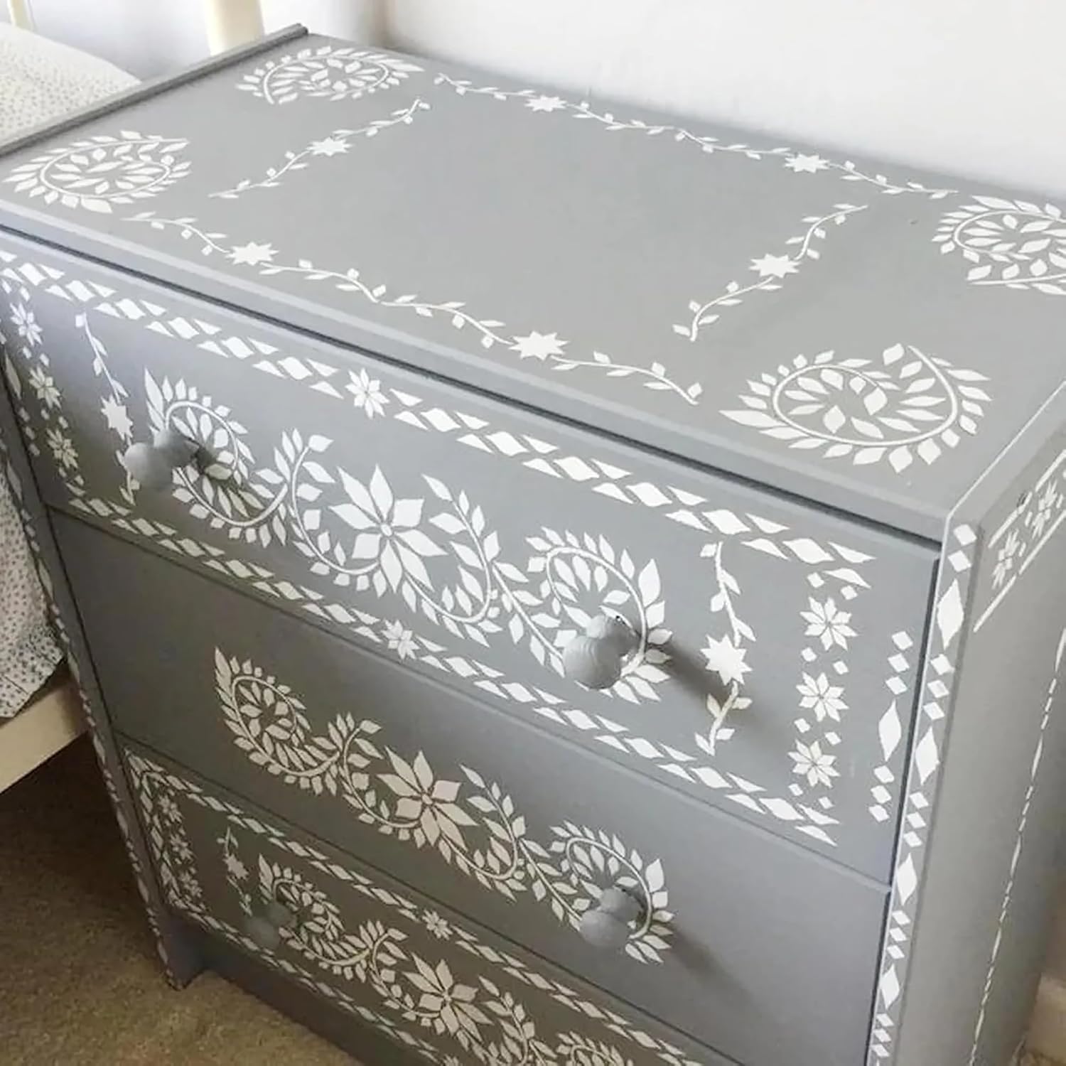 Gray dresser with white floral patterns on a neutral background