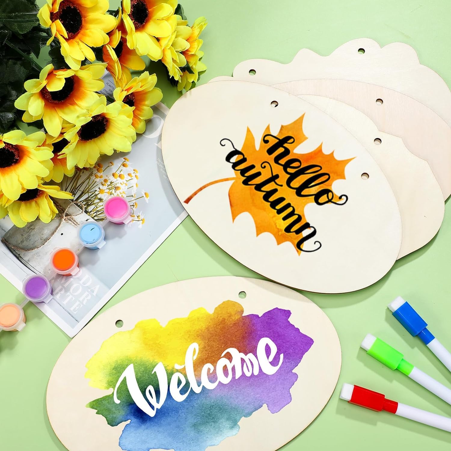 Decorative wooden signs with 'hello autumn' and 'Welcome' text, surrounded by sunflowers and markers on a green background.