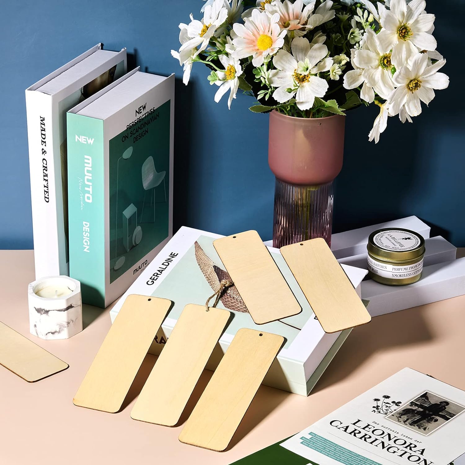 Gold bookmarks on a magazine with a vase of flowers and books in the background.